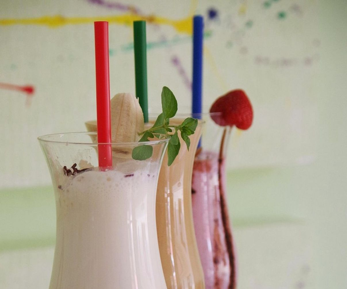 Manos preparando un smoothie de frutas en la barra